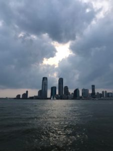 View of NYC skyline with sun breaking through clouds