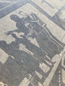 Coloured pavement is used to create an art-deco style image of a large robot talking to a woman.